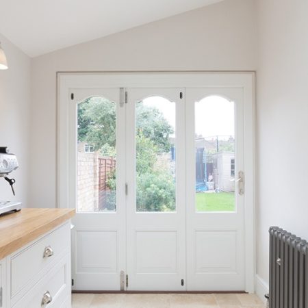 traditional style bifold doors painted white with shaped glass