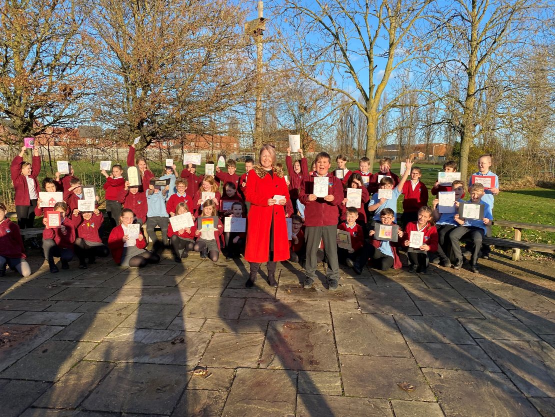 The class of Boston West Primary School celebrate as Antoni receives his prize from George Barnsdale for his winning Christmas card design.