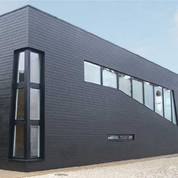 A stylish, modern home with black wood panelling, angular features and contemporary timber windows.
