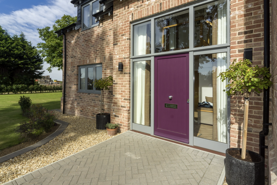 Purple contemporary style door with grey surround in barn style self-build