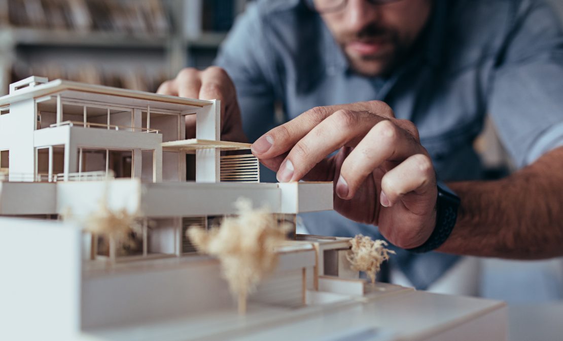 architect with model of house thinking about the environment
