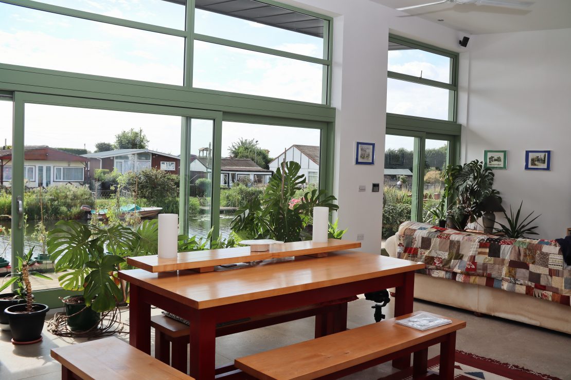 image shows pale green timber sliding patio doors in the open plan kitchen living space with views out to the river,