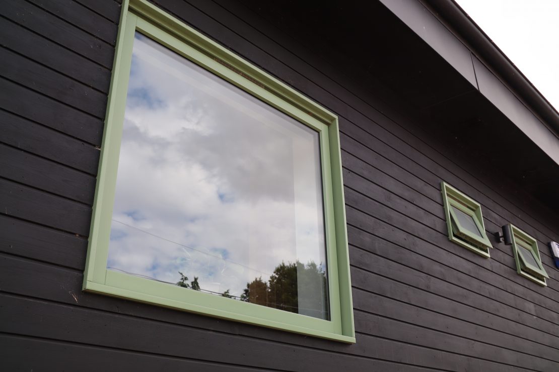 Square wooden windows with dark stained wood fascia on contemporary riverside property