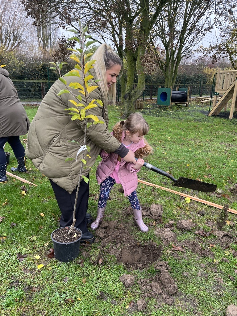 A member of the George Barnsdale team planting a tree with a child