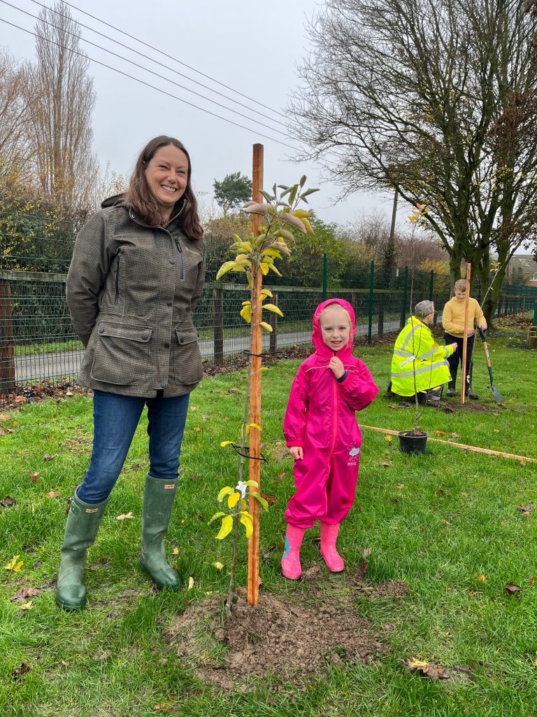 Katherine Wright helping a year 2 pupil plant a tree