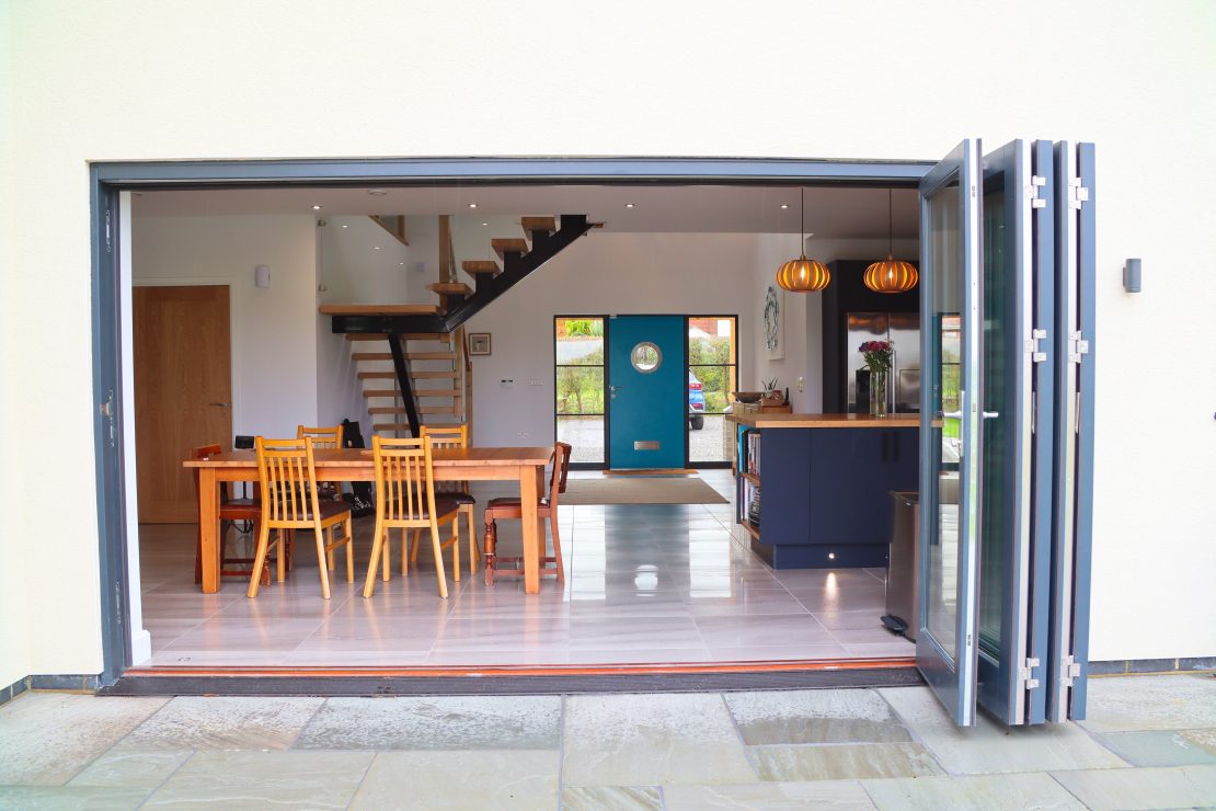 Open bifold doors from the outside into the kitchen painted dary anthracite grey
