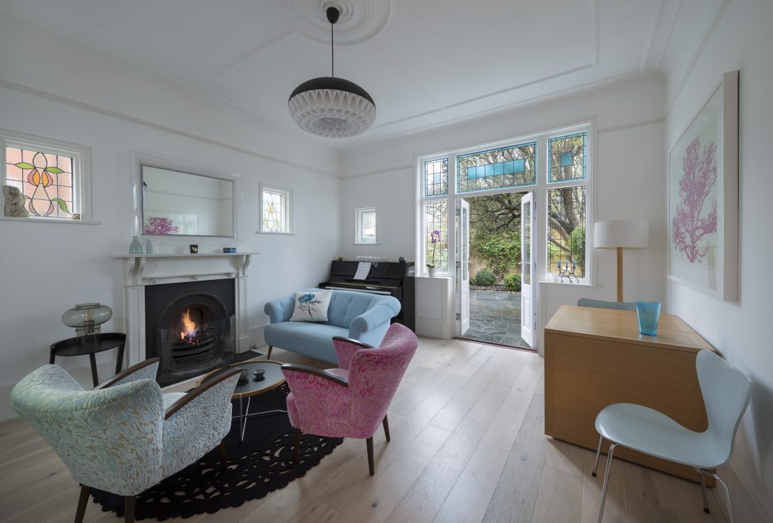 period set of timber french doors painted white with a window either side in a sitting room with open fire