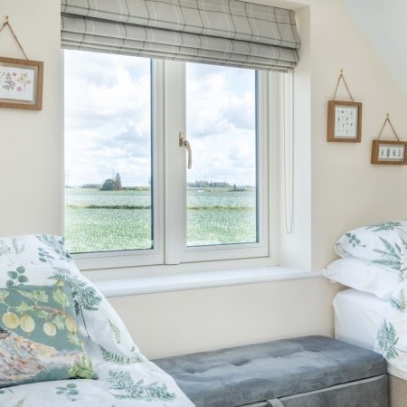 small flush casement window in a bedroom overlooking open farm land